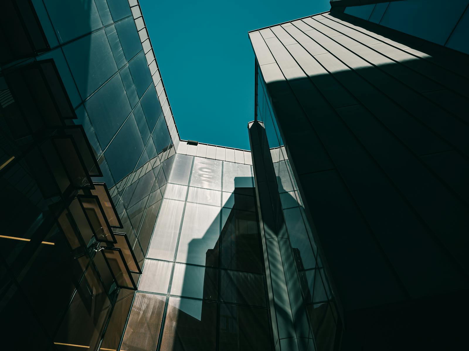 Low-angle shot of modern skyscrapers with glass panels reflecting light under a clear sky.